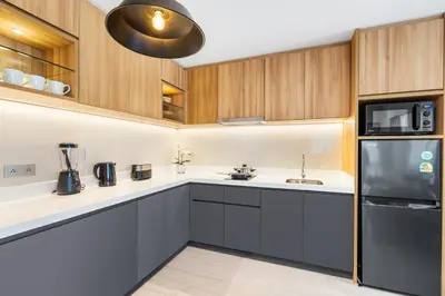 a kitchen with wooden cabinets and a black refrigerator at Laguna Lakeside BangTao by My Home Phuket in Bang Tao Beach