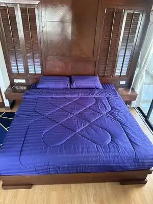 a bed with a blue comforter and a wooden headboard at Apartment in Patong Tower in Patong Beach
