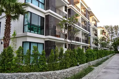 a building with a stone wall next to a street at Renovated apartment in The Title Phase I, Rawai beach in Rawai Beach