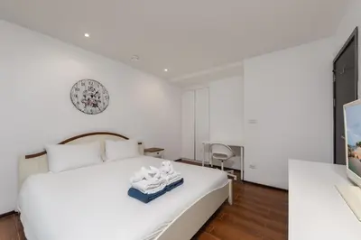 a bedroom with a white bed and a clock on the wall at Renovated apartment in The Title Phase I, Rawai beach in Rawai Beach