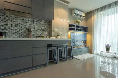 a kitchen with gray cabinets and a counter with stools at Best Facilities Fully Loaded Nicest Apartment c138 in Kamala Beach