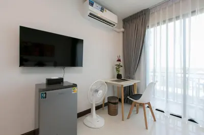 a living room with a television and a table and chairs at Wow Academy & Stay Soi Tai-Aed 2B in Ban Suan