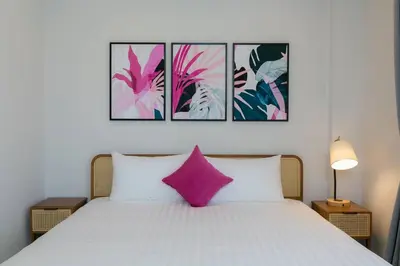 a bedroom with a white bed with a pink pillow at Wow Academy & Stay Soi Tai-Aed 3A in Ban Suan