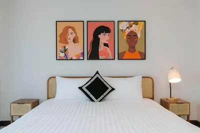 a bedroom with a white bed with four pictures on the wall at Wow Academy & Stay Soi Tai-Aed 3B in Ban Suan