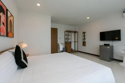 a bedroom with a white bed and a flat screen tv at Wow Academy & Stay Soi Tai-Aed 3B in Ban Suan