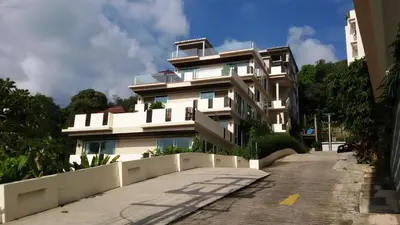 a large white building next to a street at Karon Suite Apartment in Karon Beach
