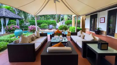 an outdoor patio with couches and an umbrella at Charming Chom Tawan Villa 3 bdr in Layan Beach
