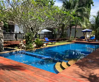 a swimming pool with blue water and a wooden deck at Isle Beach Resort Krabi-SHA in Klong Muang Beach