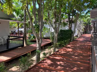a wooden walkway with trees on the side of a house at Isle Beach Resort Krabi-SHA in Klong Muang Beach