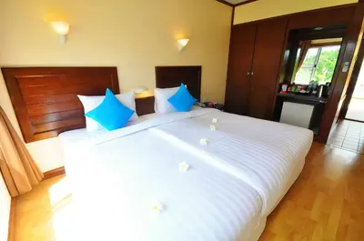 a large white bed with blue pillows in a bedroom at Isle Beach Resort Krabi-SHA in Klong Muang Beach