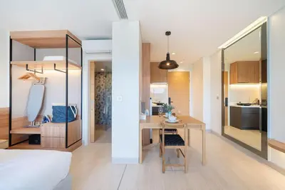 a bedroom with a desk and a bed and a kitchen at New 1 br studio in Laguna Phuket in Phuket Town