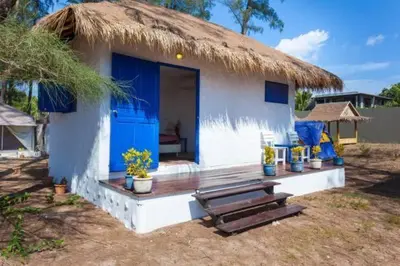 a small house with blue doors and a thatched roof at Micky Monkey Beach Hotel Phuket Maikhao Thailand in Mai Khao Beach