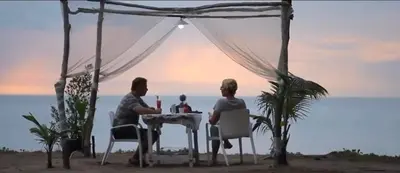 two people sitting at a table on the beach at Micky Monkey Beach Hotel Phuket Maikhao Thailand in Mai Khao Beach
