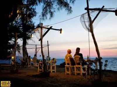 a group of people sitting in chairs on the beach at Micky Monkey Beach Hotel Phuket Maikhao Thailand in Mai Khao Beach