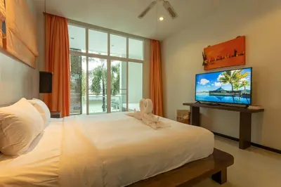 a bedroom with a white bed and a flat screen tv at Oxygen 3BR Walk to Shops, Bars, Private Pool v113 in Rawai Beach