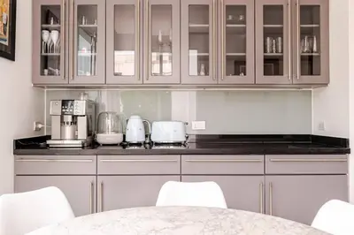 a kitchen with white cabinets and a table with chairs at Kyerra 88-16 An exquisite mansion with eclectic interiors in Phuket Town
