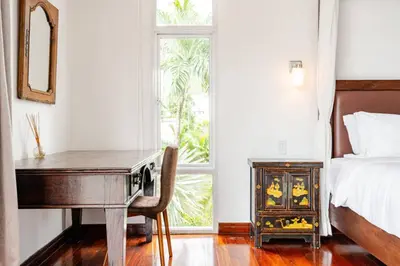 a bedroom with a desk and a bed and a window at Kyerra 88-16 An exquisite mansion with eclectic interiors in Phuket Town