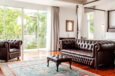 a living room with a leather couch and a bed at Kyerra 88-16 An exquisite mansion with eclectic interiors in Phuket Town