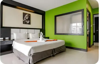 a bedroom with a large bed with a green wall at The Star House in Patong Beach