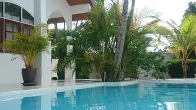 a swimming pool with palm trees and a building at Villa Happy home in Rawai Beach