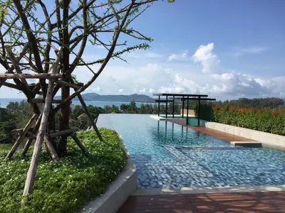 a infinity pool with a tree and a pavilion at Cozy Surin apartment at 6 Avenue by Lofty in Surin Beach