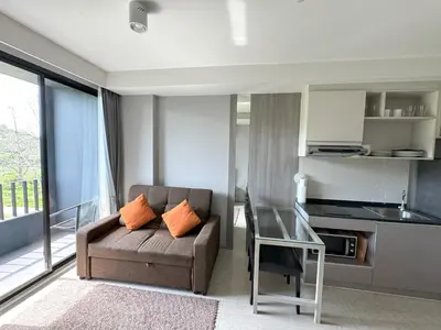 a living room with a couch and a glass table at Cozy Surin apartment at 6 Avenue by Lofty in Surin Beach