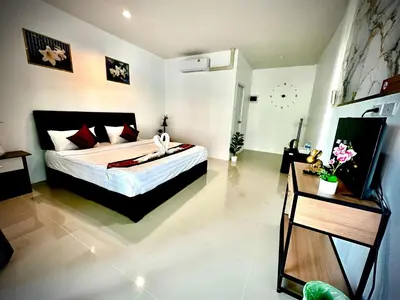 a bedroom with a bed and a clock on the wall at Da Airport Hotel in Nai Yang Beach