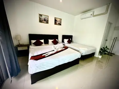 a bedroom with two beds with white sheets and red pillows at Da Airport Hotel in Nai Yang Beach