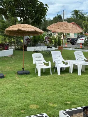 a group of white chairs and umbrellas on the grass at Da Airport Hotel in Nai Yang Beach