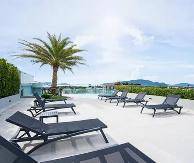 a row of benches sitting on a patio with a palm tree at Modern Condo near the Beach - NV531 in Phuket Town