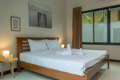 a bedroom with a bed with white sheets and a window at 2 Beds large pool night market Soi Namjai v122 in Rawai Beach