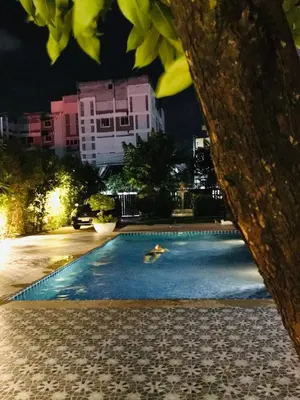 a person swimming in a swimming pool at night at Studio Room with private kitchen and Bathroom in Ban Phlu Yai