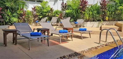 a row of chairs and tables next to a pool at Karon Pool Hotel in Karon Beach