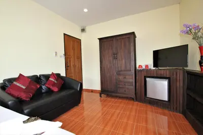 a living room with a black leather couch and a television at Karon Pool Hotel in Karon Beach