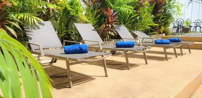 a row of lounge chairs with blue pillows on them at Karon Pool Hotel in Karon Beach
