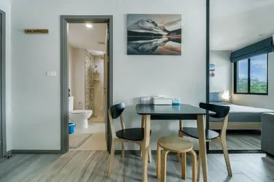 a dining room with a table and chairs and a bedroom at Cozy Studio Apartment at Naiyang Beach G507 in Phuket Town