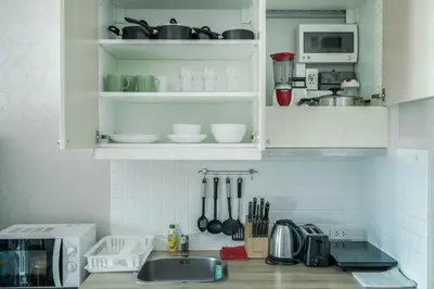 a kitchen with white cabinets and a sink with utensils at Cozy Studio Apartment at Naiyang Beach G507 in Phuket Town