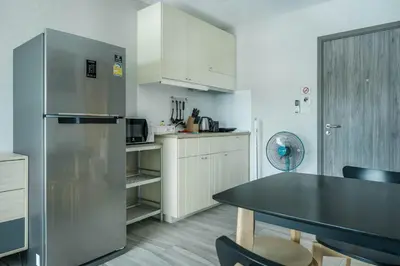 a kitchen with a table and a refrigerator at Cozy Studio Apartment at Naiyang Beach G507 in Phuket Town