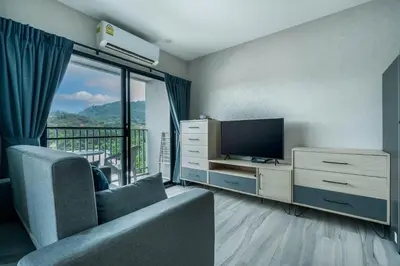 a living room with a couch and a television at Cozy Studio Apartment at Naiyang Beach G507 in Phuket Town