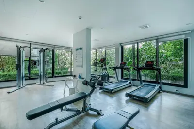 a gym with treadmills and ellipticals in a room with windows at Cozy Studio Apartment at Naiyang Beach G507 in Phuket Town
