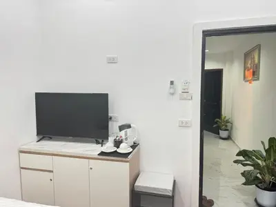a living room with a television on a white wall at Heaven House Restro & Bar in Patong Beach