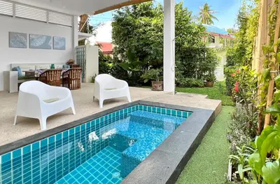a swimming pool in a backyard with two chairs and a table at At the Beach New comfortable Pool Home, Ao Yon Beach, Phuket in Ban Ao Makham