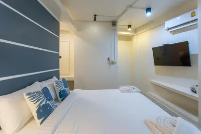 a small bedroom with a bed and a sink at The Light House at Town Phuket in Phuket Town
