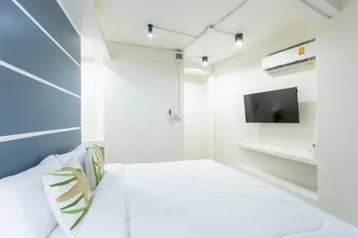 a white room with a bed and a tv at The Light House at Town Phuket in Phuket Town