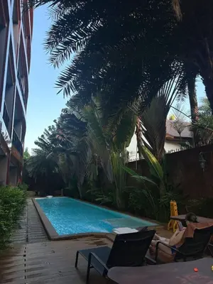 a woman laying in chairs next to a swimming pool at Nai Harn Beach Condo (P1) in Rawai Beach