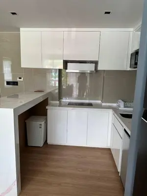 a white kitchen with white cabinets and a wooden floor at Spacious apartment 600m from the beach in Rawai Beach