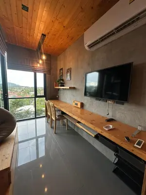 a room with a wooden table with a tv on the wall at ReLife The Windy NaiHarn (716) in Ban Saiyuan (1)