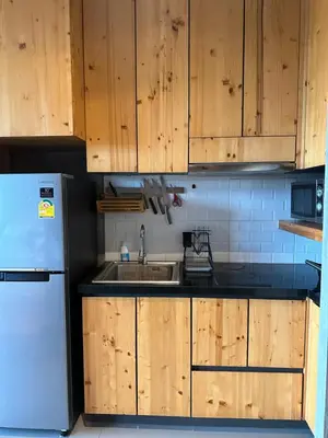 a kitchen with wooden cabinets and a sink and a refrigerator at ReLife The Windy NaiHarn (716) in Ban Saiyuan (1)
