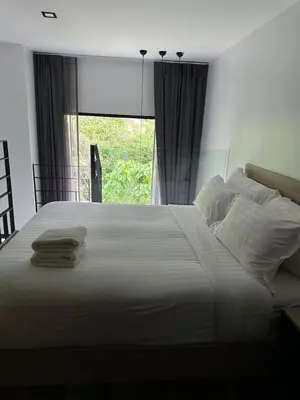 a large white bed in a bedroom with a window at Utopia Naiharn Beach B17 in Rawai Beach