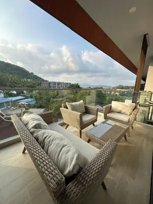 a balcony with wicker furniture and a large window at Palmyrah Surin sea view in Surin Beach